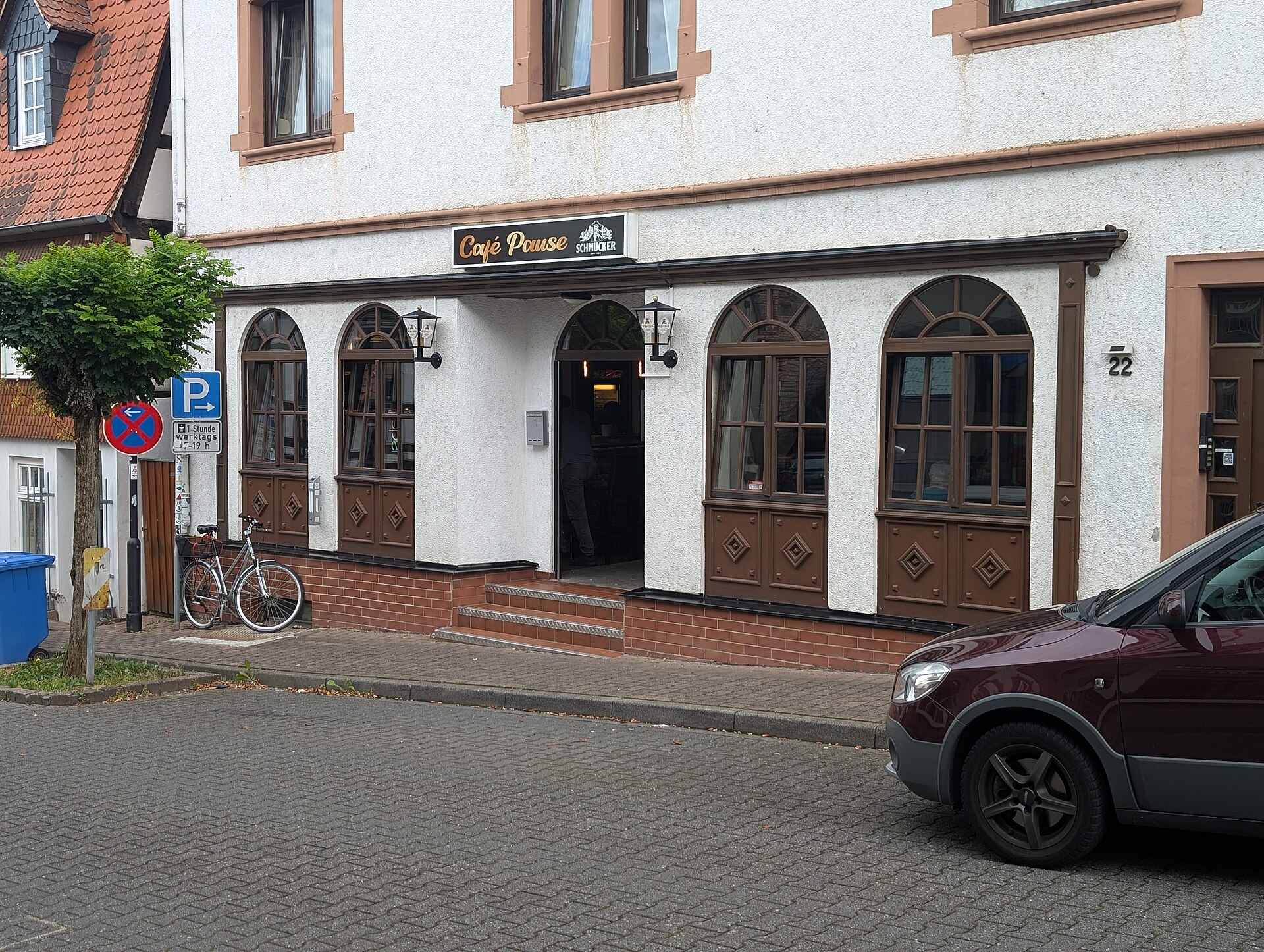 A street scene shows Cafe Pause Schneider, highlighting a moment of pause before asking questions.