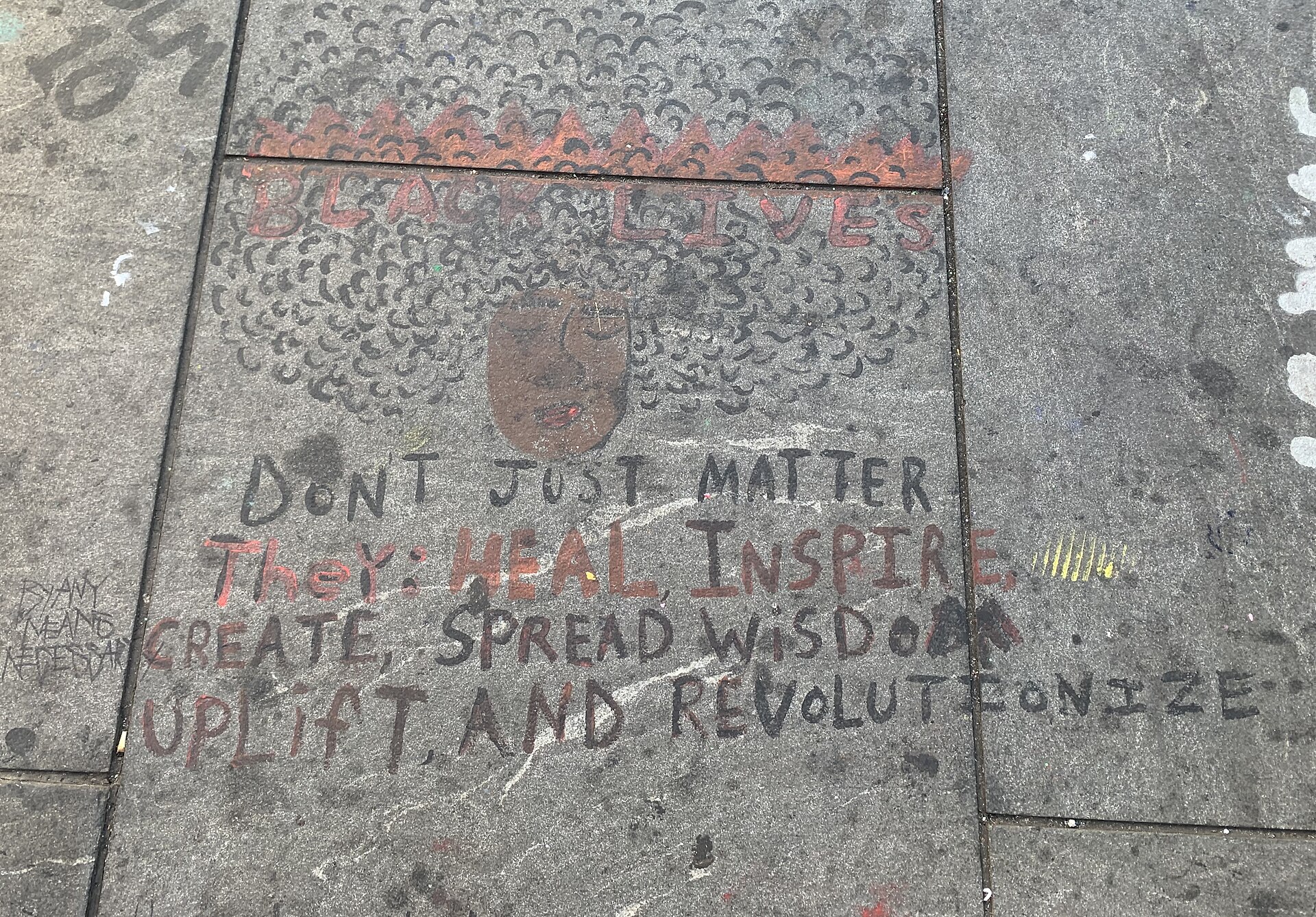 Colorful sidewalk chalk art displays a message of empowerment, healing and wisdom, reflecting themes of social justice.